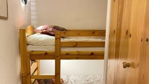 A bunk bed with a wooden frame, white bedding, and a plaid blanket. - Apartment near Piste de Tracouet (Haute-Nendaz)