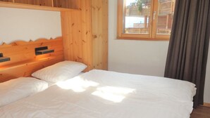 A wooden-paneled room with a bed, a window with curtains, and a view of a fence outside. - Apartment in Nendaz by Ski Slopes (Haute-Nendaz)