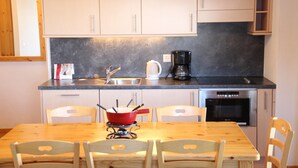 Una cocina con mesa y sillas de madera, cafetera y microondas.