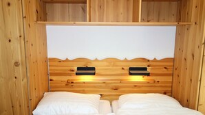 A wooden cabin-style bedroom with two beds, a wooden headboard, and built-in shelves. - Charming apartment with balcony (Haute-Nendaz)