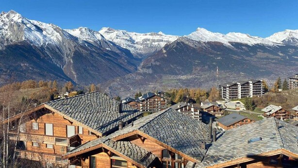 Un complejo turístico de montaña con cabañas de madera y vistas a picos nevados.