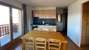 Cocina compacta con una mesa y sillas, cafetera y armarios.