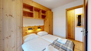 A wooden room with two beds, a wooden wardrobe, and a mirror on the wall. - Apartment in Nendaz near Cable Car (Haute-Nendaz)