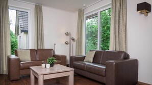 A living room with two brown leather sofas, a wooden coffee table, and a radiator.