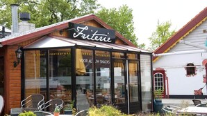 A wooden exterior of a restaurant named 'Friterie' with large glass windows and outdoor seating.
