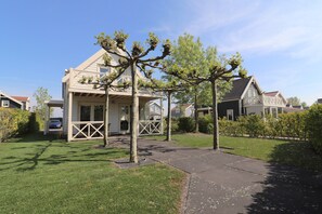 A two-story house with a porch, a driveway, and a well-maintained lawn. - Bungalow in South Holland by the Water (Simonshaven)