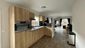 Una cocina moderna con armarios de madera, horno empotrado y comedor con mesa y sillas.