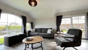 Un salon moderne avec un canapé gris, une table basse ronde et un fauteuil noir.