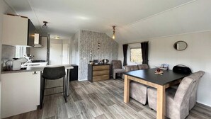 Une cuisine moderne avec un coin repas, un plancher en bois et une cuisinière intégrée.