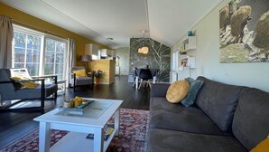 A modern living room with a grey sofa, a white coffee table, and a dining area in the background.