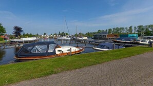 A canal with boats docked, a grassy area, and a brick pathway.