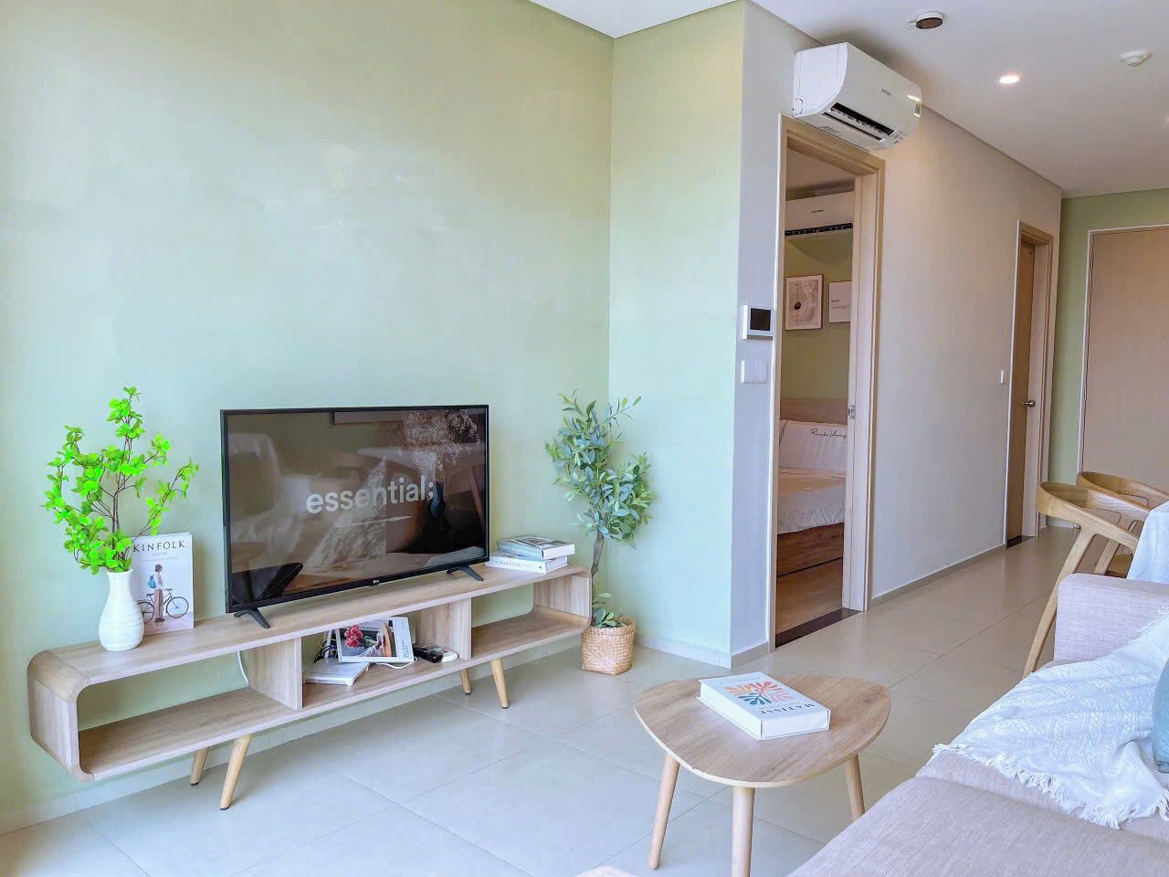 A modern living room with a flat-screen TV, wooden entertainment unit, a round coffee table, and a sofa.