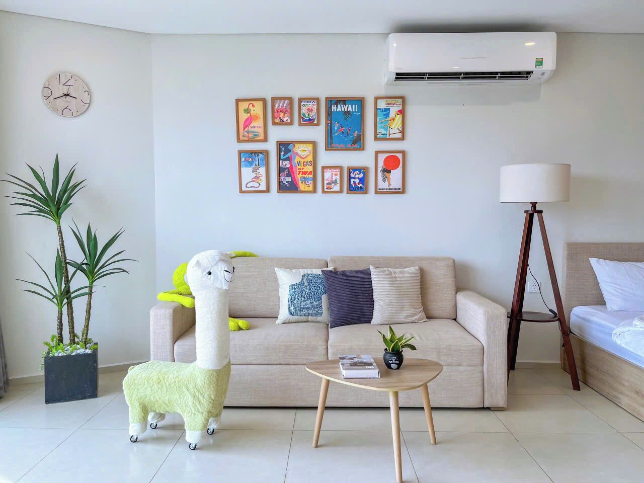 Un salon comprenant un canapé, une table basse, une lampe, une horloge murale et une rangée de tableaux encadrés.