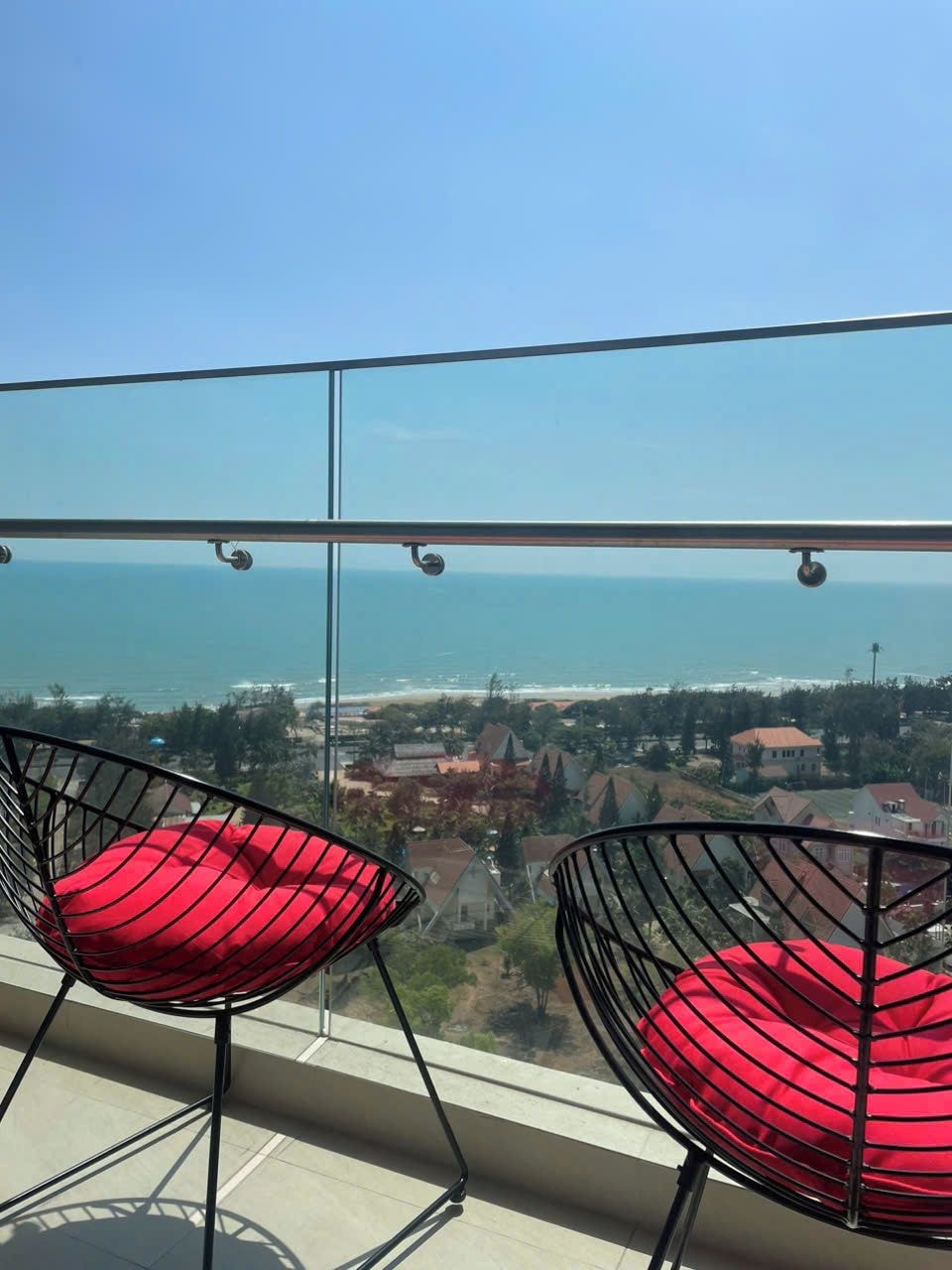 Un balcone con due sedie e vista sul mare e sugli edifici.