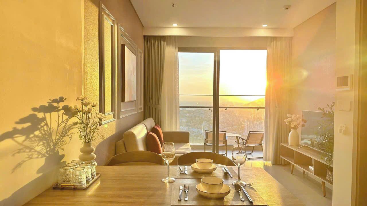 Quarto de hotel moderno com área de refeições, um sofá e uma varanda com vista para a cidade.
