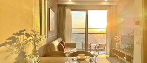 Quarto de hotel moderno com área de refeições, um sofá e uma varanda com vista para a cidade.