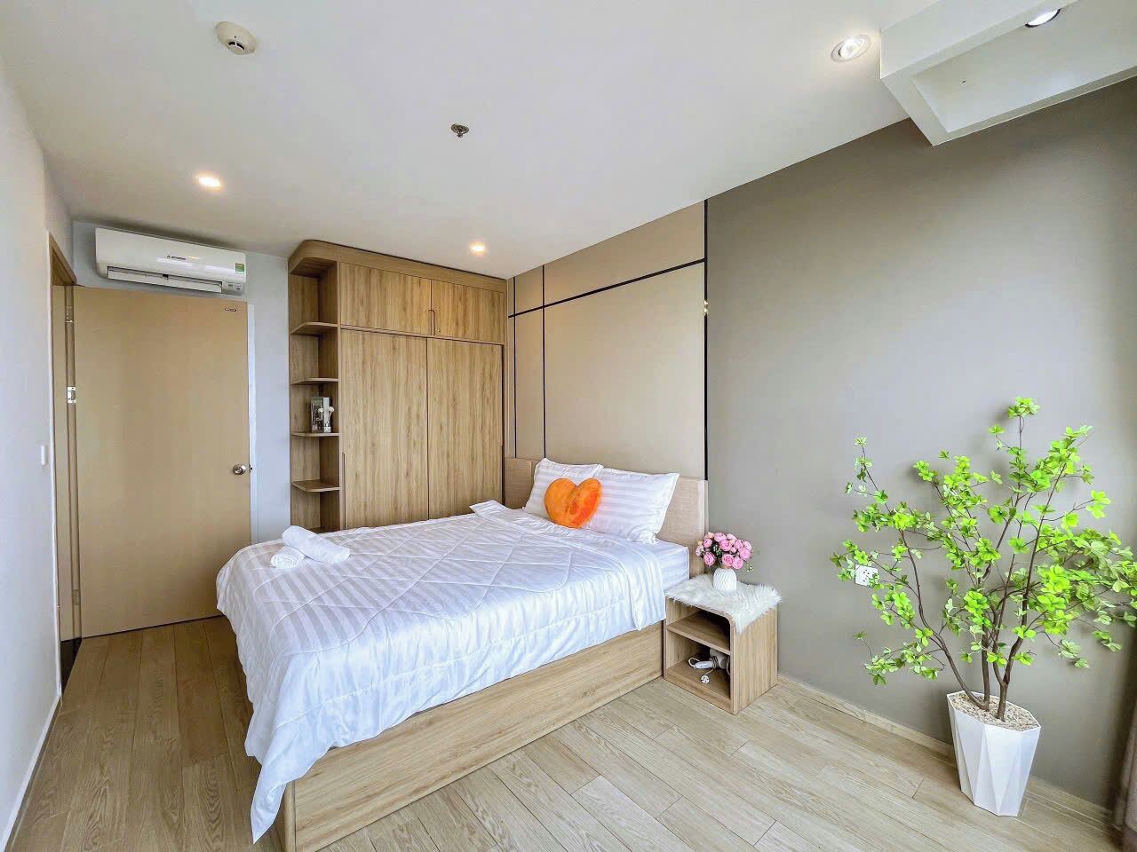 Un dormitorio moderno con cama, armario empotrado, mesita de noche y una planta en maceta.