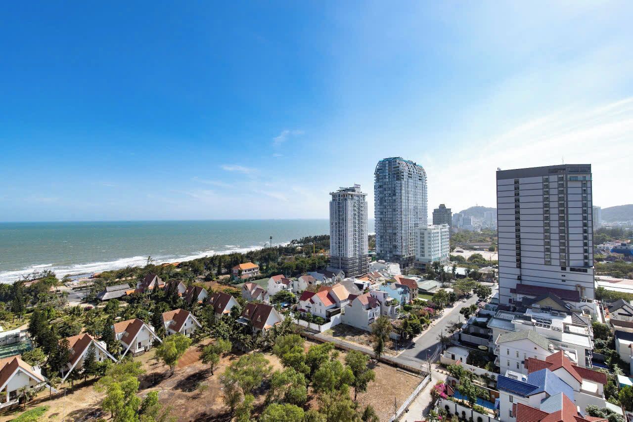 A coastal cityscape with residential buildings, a beach, and high-rise buildings.