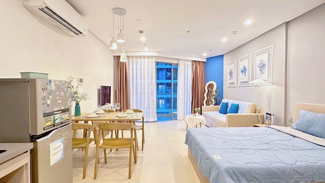 Quarto de hotel moderno com cama, área de refeições e vista para a paisagem urbana.