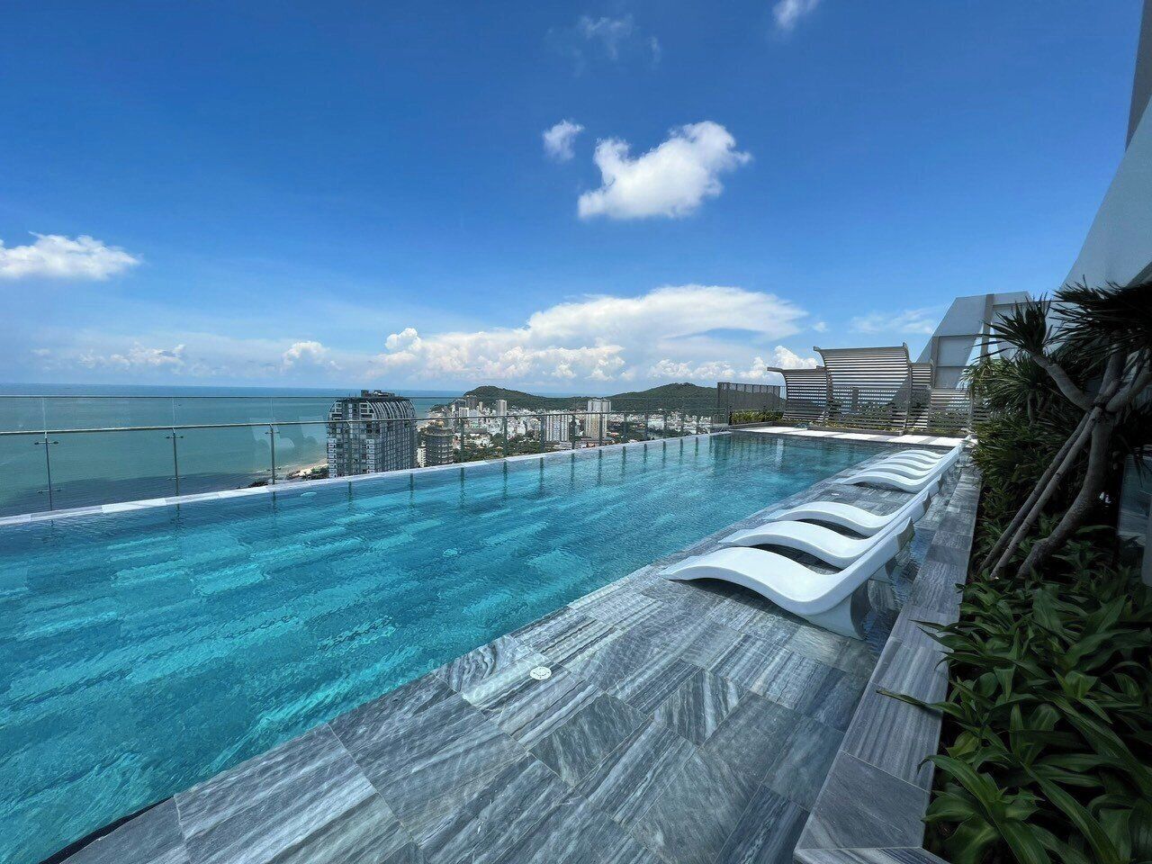 A rooftop infinity pool with a clear view of the ocean and cityscape.