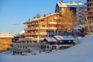 A multi-story wooden building with balconies, surrounded by snow. - Spacious apartment with terrace (Haute-Nendaz)