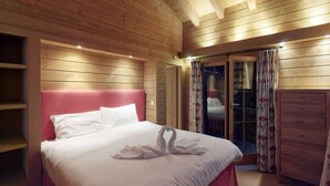A wooden-paneled bedroom with a bed, a wardrobe, and a sliding glass door. - Chalet in Nendaz near Ski Slopes (Haute-Nendaz)
