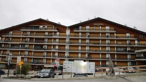 A multi-story hotel with balconies, a sign reading "Almaviva," and a parking area with cars. - Studio in Nendaz near Ski Lift (Haute-Nendaz)