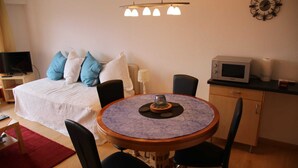 A bedroom with a bed, a round dining table with chairs, a television, a microwave, and a clock on the wall. - Studio in Nendaz near Ski Lift (Haute-Nendaz)