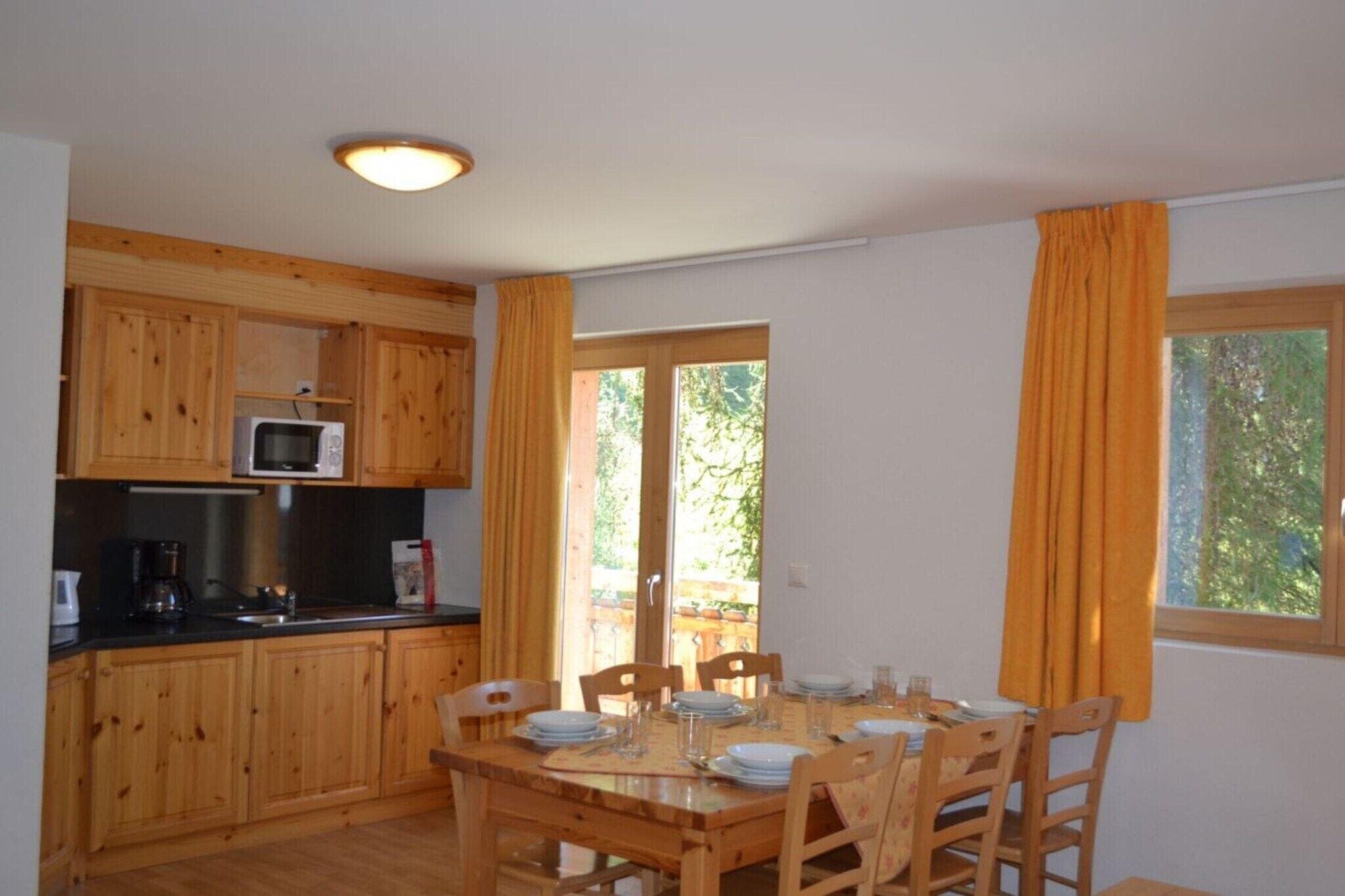 A wooden kitchen with a microwave, coffee maker, and dining table set for four.