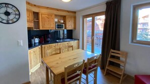 A compact kitchen with wooden cabinets, a microwave, and a dining area with a table and chairs.