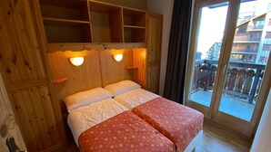 Une pièce en bois avec un lit, deux appliques murales et un balcon doté d’une balustrade en bois.