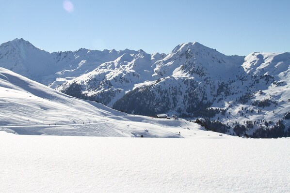 A snow-covered mountain landscape with ski slopes and a clear sky.