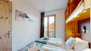 A hotel room with two beds, a wooden bunk bed, a window with a view of the mountains, and a painting on the wall. - Appealing apartment with balcony (Haute-Nendaz)