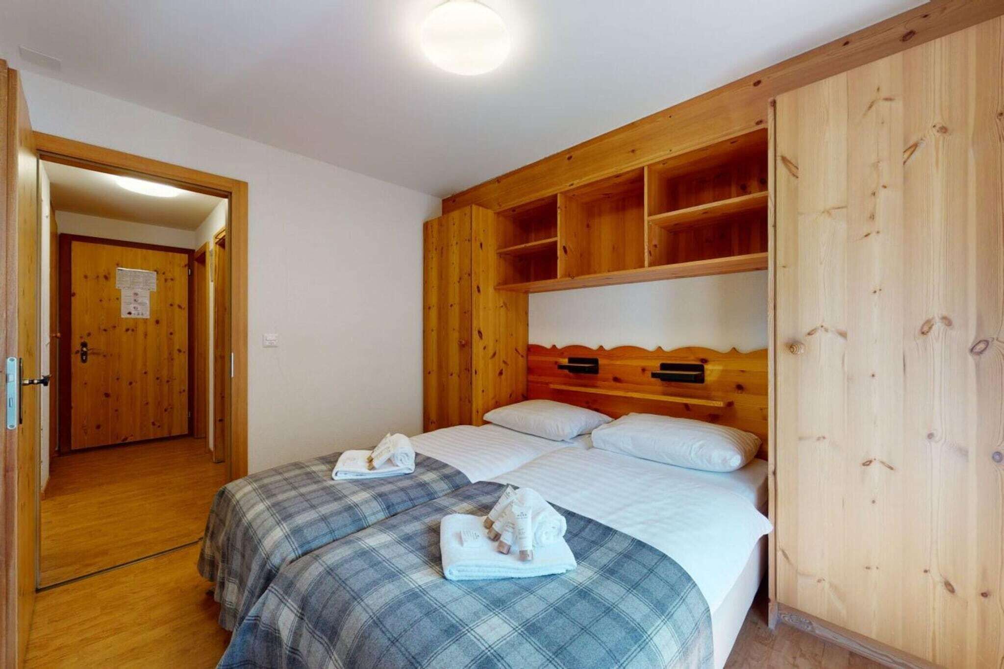 Une chambre avec deux lits, une tête de lit en bois et une armoire en bois.