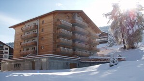 A multi-story wooden building with balconies, surrounded by snow. - Amazing apartment with terrace (Haute-Nendaz)