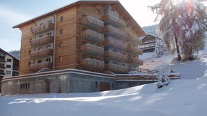 A multi-story wooden building with balconies, set in a snowy environment. - Amazing apartment with terrace (Haute-Nendaz)