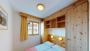Quarto com cama, cabeceira de madeira, abajures, janela com cortinas e um quadro na parede.
