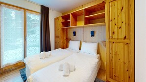 A hotel room with two beds, wooden paneling, and a large window with curtains. - Lovely apartment with valley view (Haute-Nendaz)