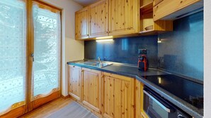 A kitchen with wooden cabinets, a black countertop, and a stove. - Lovely apartment with valley view (Haute-Nendaz)