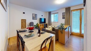 A modern living room with a dining area, a TV, and a plant. - Lovely apartment with valley view (Haute-Nendaz)