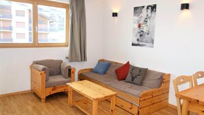 Une pièce chaleureuse avec un canapé en bois, une chaise en bois, une table en bois et une fenêtre avec des rideaux.