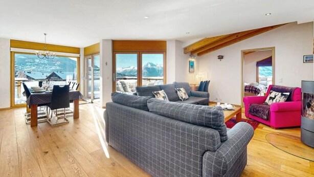 A spacious living area with a large gray sofa, a pink couch, and a dining table with chairs. - Mountain apartment with parking (Veysonnaz)