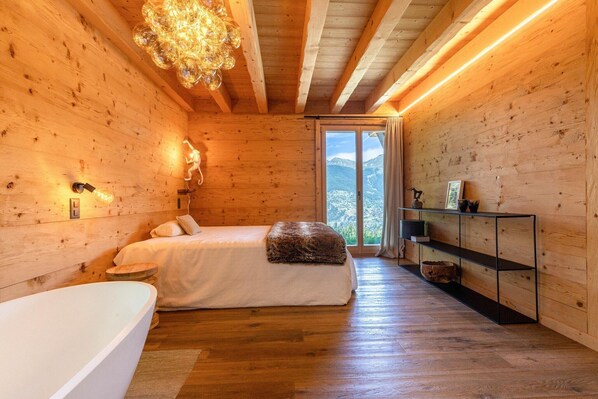 A wooden cabin bedroom with a bed, bedside lamps, a glass shelf, and a view of the outdoors.