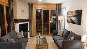 A living room with two sofas, a coffee table, a TV, and a sliding glass door leading to a balcony. - Apartment for 8 in Veysonnaz (Veysonnaz)