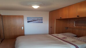 A bedroom with a bed, wooden wardrobe, and a painting on the wall. - Apartment for 8 in Veysonnaz (Veysonnaz)
