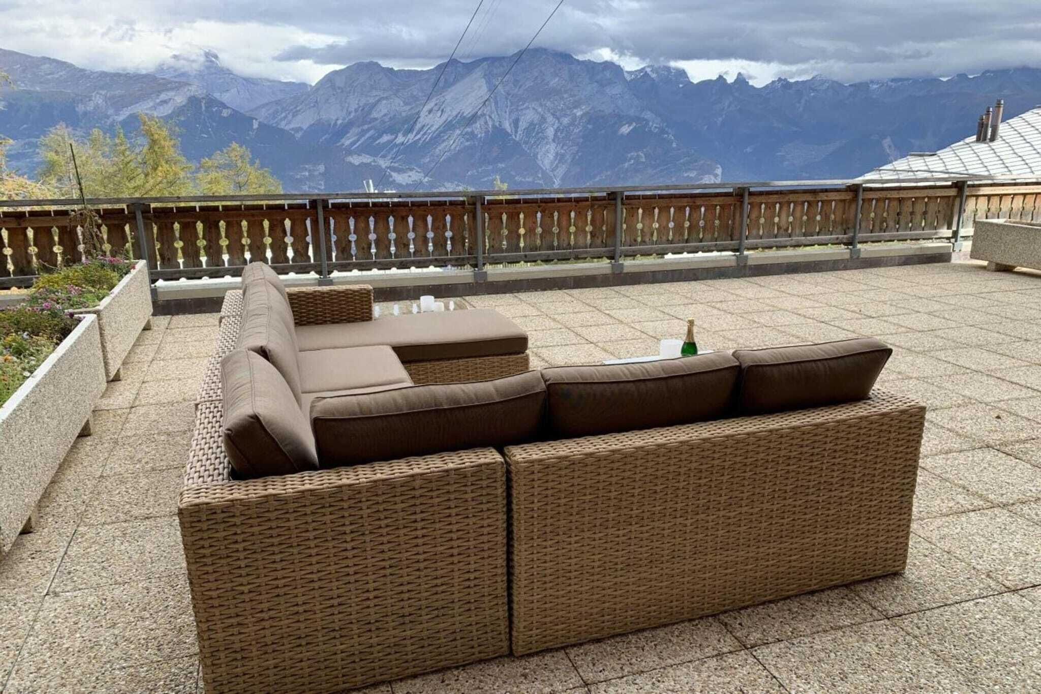 A wicker sofa on a terrace with a mountain view.