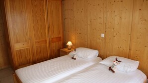 Ein Zimmer mit zwei Betten, einem Holzschrank und einem Nachttisch mit Lampe.
