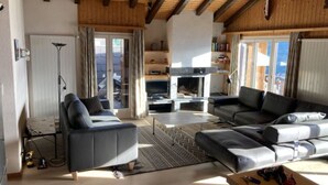 A living room with a fireplace, sofas, and a view of the mountains. - Family apartment with terrace (Veysonnaz)
