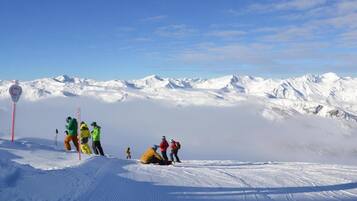 A snowy mountain landscape with skiers and a red signpost.