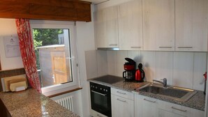 A kitchen with white cabinets, a granite countertop, a built-in oven, a coffee maker, and a sink.